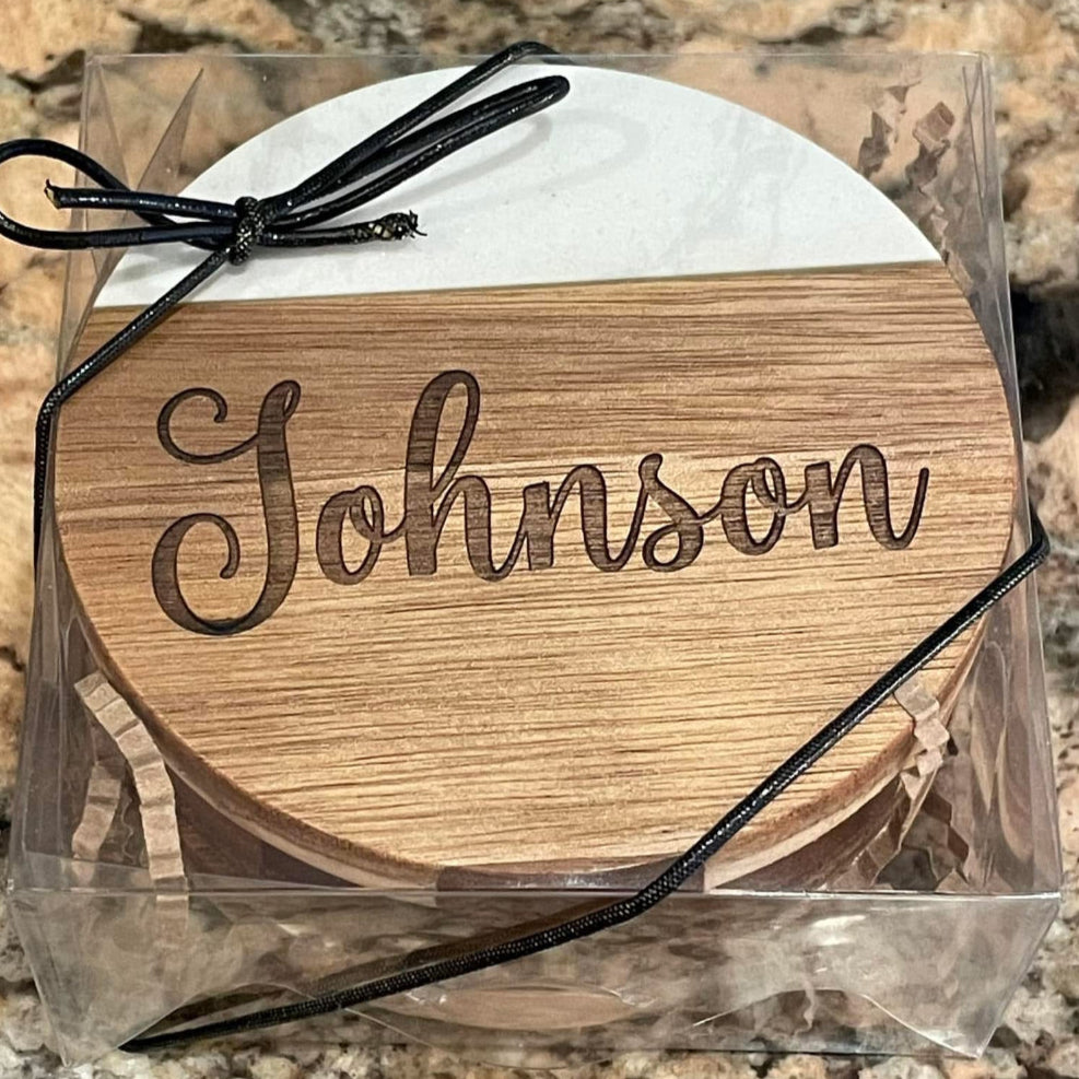 Wooden coaster set with 'Johnson' engraving in clear packaging on a granite surface